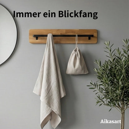 Handtuchstange aus Holz an grauer Wand mit Leinentuch, Stoffbeutel