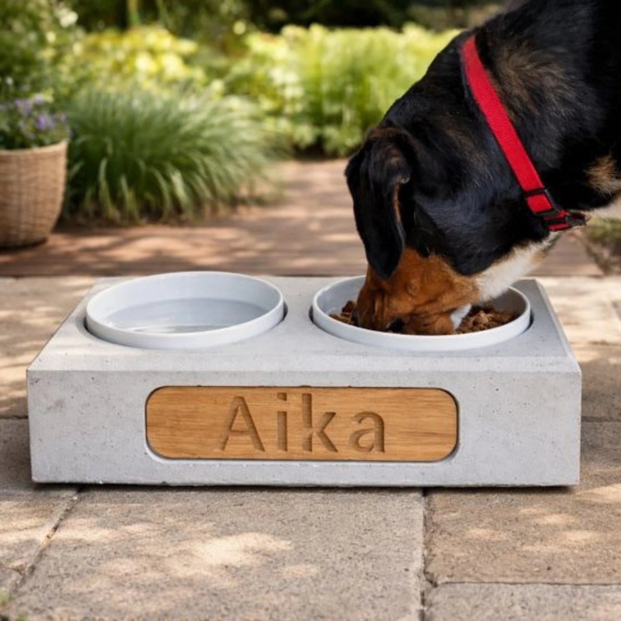 Futterstation für Hunde aus Beton mit Eichenholz-Gravur, Hund frisst draußen auf Terrasse
